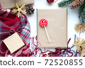 Present in brown craft paper, boxes, candy, plaid and Christmas decoration on table. Copy space. Eco friendly New Year 72520855