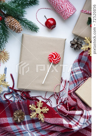 Present in brown craft paper, boxes, candy, plaid and Christmas decoration on table. Copy space. Eco friendly New Year 72520856