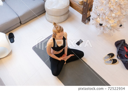 Beautiful blonde woman doing home workout indoors. Woman practice yoga at home. Fit girl using workout tutorials for healthy active lifestyle. Woman using quarantine for home workouts. 72522934