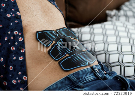 man using an electrical muscle stimulation device man using an electrical muscle stimulation device 72523919