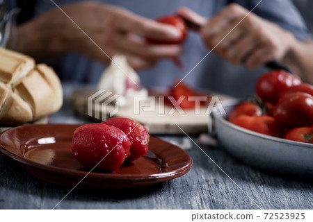 man peeling scalded tomatoes 72523925