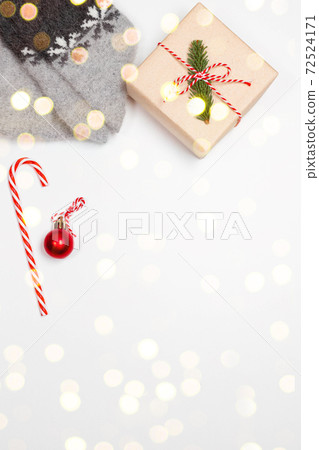 Top view of warm socks with snowflakes , surprise gift box wrapped in kraft paper and bow on gray background. Christmas minimal composition with blurred lights Top view of warm socks with snowflakes , surprise gift box wrapped in kraft paper and bow on gray background. Christmas minimal composition with blurred lights 72524171