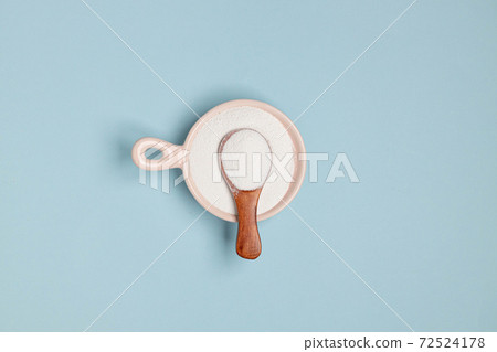 Collagen powder in a glass bowl and small wooden spoon on blue background. Top view, space for text. Healthy lifestyle concept. Horizontal minimal banner Collagen powder in a glass bowl and small wooden spoon on blue background. Top view, space for text. Healthy lifestyle concept. Horizontal minimal banner 72524178