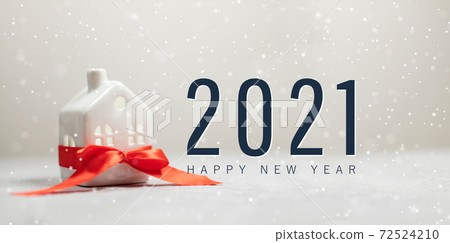 Merry christmas and happy new year horizontal banner with small toy model house wrapped in red satin ribbon on beautiful white background Merry christmas and happy new year horizontal banner with small toy model house wrapped in red satin ribbon on beautiful white background 72524210