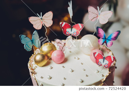 Pastel colors tasty cake with butterfly. White, yellow, pink and blue cream custard. White background. Selective focus.. 72524420