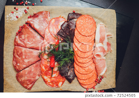 Cutting board with prosciutto, salami, cheese,bread sticks and olives on dark stone background. From top view. 72524505