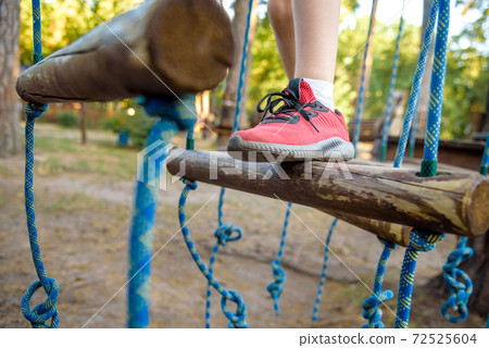 Boy foot shoe close up in adventure climbing high wire park - people on course in mountain helmet and safety equipment 72525604