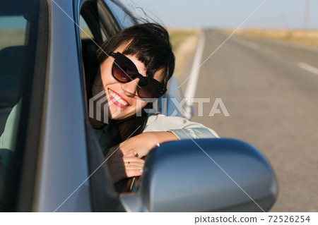 A brunette woman looks out of the window of an actomobile A brunette woman looks out of the window of an actomobile 72526254