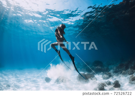 Woman freediver glides with sand over sandy bottom. Freediving underwater in Hawaii island Woman freediver glides with sand over sandy bottom. Freediving underwater in Hawaii island 72526722