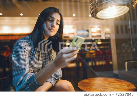 brunette girl using her cellphone to reach a friend brunette girl using her cellphone to reach a friend 72527843