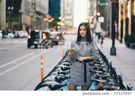 girl renting a city bike from a bike stand girl renting a city bike from a bike stand 72527847