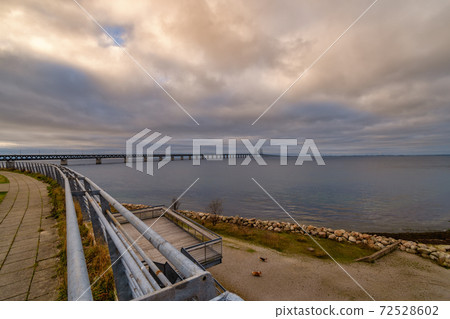 The Oresund Bridge, the bridge and underwater tunnel connecting Malmo, Sweden with Copenhagen, Denmark. A beautiful sunset sky in the background The Oresund Bridge, the bridge and underwater tunnel connecting Malmo, Sweden with Copenhagen, Denmark. A beautiful sunset sky in the background 72528602