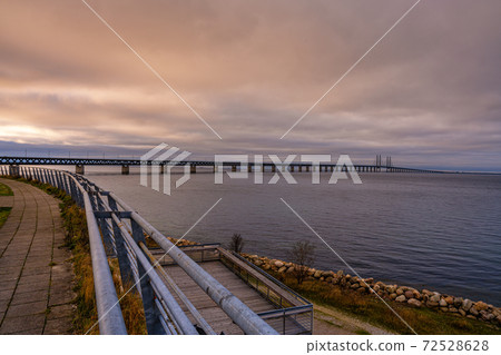 The Oresund Bridge, the bridge and underwater tunnel connecting Malmo, Sweden with Copenhagen, Denmark. A beautiful sunset sky in the background 72528628