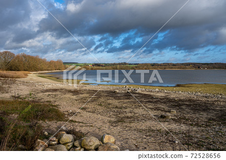 A shoreline at a lake with a dramatic sky in the background. Picture from Lake Vomb, Scania, Sweden A shoreline at a lake with a dramatic sky in the background. Picture from Lake Vomb, Scania, Sweden 72528656