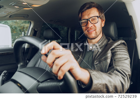 Confident young man sitting in a car 72529239