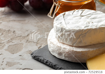 Cheese served with grapes and honey on grey surface Cheese served with grapes and honey on grey surface 72529518