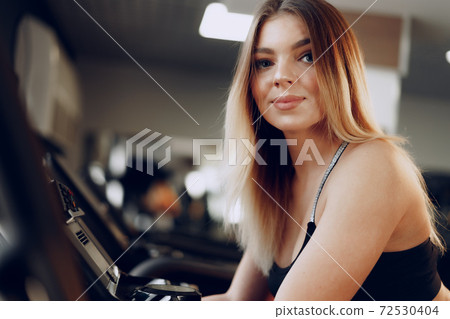 Fit curvy young blonde woman training in a cardio zone in a gym Fit curvy young blonde woman training in a cardio zone in a gym 72530404