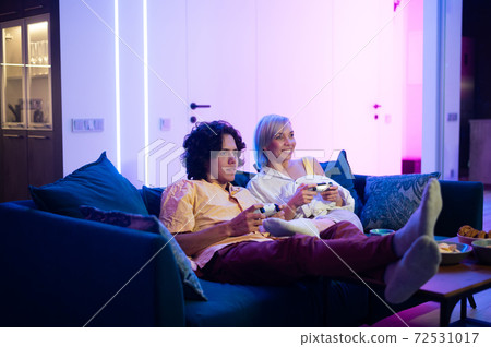 Young cheerful Caucasian husband and wife play videogames against each other at home enjoying leisure time 72531017