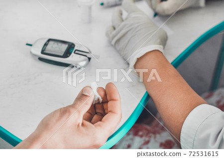 Blood glucose meter, glucometer and patient, the procedure takes place in the laboratory. Blood glucose meter, glucometer and patient, the procedure takes place in the laboratory. 72531615