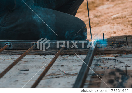 Welding a metal profile at home, a man welds metal to design an aviary for a dog. 72531663