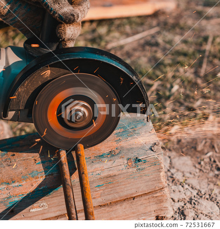 The worker cuts the metal with an angle grinder, the work is carried out on the street. The worker cuts the metal with an angle grinder, the work is carried out on the street. 72531667