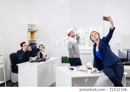 Employees having fun in the office, posing and taking selfies wi 72532106