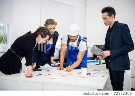 A creative team of business people at the meeting in the conference room. Two successful businesswomen and two businessmen around the desk, discussing new projects 72532300