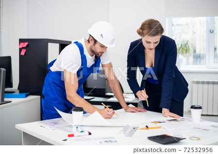 Two architects, a man and a woman, working on a construction pro 72532956