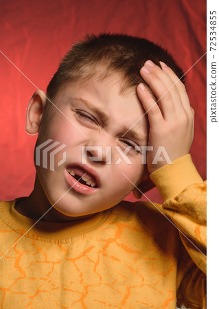 The little boy shows headache and gestures with his hands, resting them on his head. The little boy shows headache and gestures with his hands, resting them on his head. 72534855