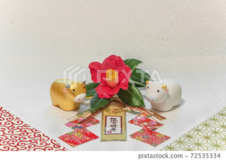 A greeting card with a camellia flower, a cute cow figure of the year of the ox, and a decoration that says Happy New Year. 72535334