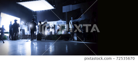 Silhouette images of video production behind the scenes or b-roll or making of TV commercial movies that film crew team lightman and videos cameraman working together with movie director in studio. 72535670