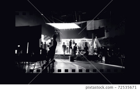 Silhouette images of video production behind the scenes or b-roll or making of TV commercial movies that film crew team lightman and videos cameraman working together with movie director in studio. 72535671