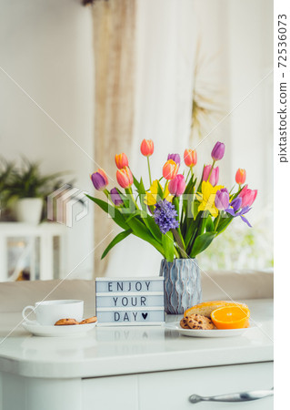 Good morning concept. Romantic breakfast - fresh flowers, cup of hot drink, cookies, orange, lightbox with message Enjoy your day on marble table with light interior view. Vertical card. Copy space. Good morning concept. Romantic breakfast - fresh flowers, cup of hot drink, cookies, orange, lightbox with message Enjoy your day on marble table with light interior view. Vertical card. Copy space. 72536073