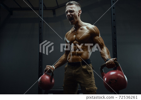 Fitness man pumping up muscles with kettlebell Fitness man pumping up muscles with kettlebell 72536261