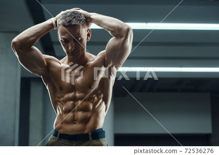 Fitness man pumping up abs muscles in gym 72536276