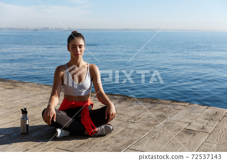 High angle shot of beautiful relaxed woman having yoga training near the sea, meditating on a pier 72537143