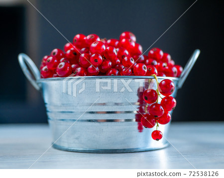 A metal basin filled with red currants 72538126
