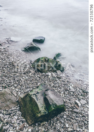 Row of boulders in foam of waves Row of boulders in foam of waves 72538796