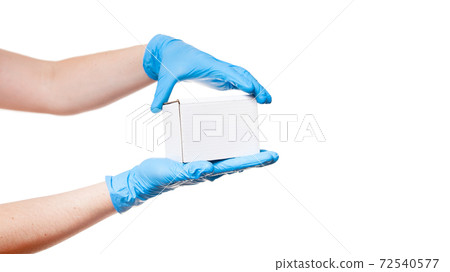 Delivery man hands in blue sterile gloves holds white label cardboard box, safe delivery during quarantine stay home, concept banner on medical theme isolated on white background with copy space. Delivery man hands in blue sterile gloves holds white label cardboard box, safe delivery during quarantine stay home, concept banner on medical theme isolated on white background with copy space. 72540577