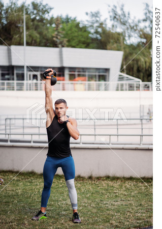 Sportive guy training with kettlebell. Strength and motivation. 72540637