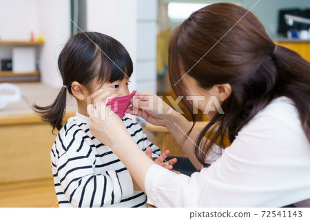媽媽在她的孩子上戴口罩 72541143