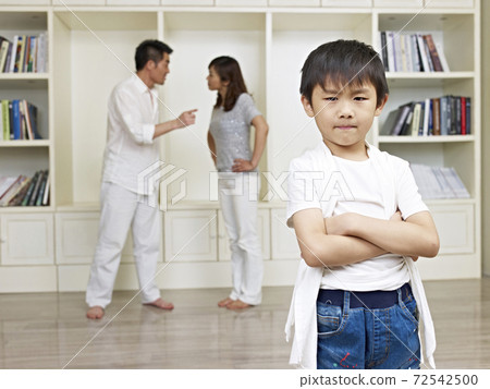 six-year old asian boy with quarreling parents in background. six-year old asian boy with quarreling parents in background. 72542500