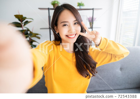 Pretty young asian female with big smile sitting at living room 72543388