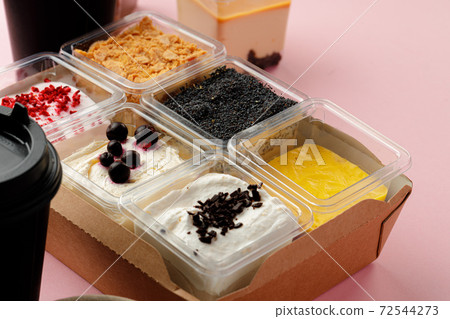 Mousse desserts in square plastic boxes with different toppings on pink table Mousse desserts in square plastic boxes with different toppings on pink table 72544273