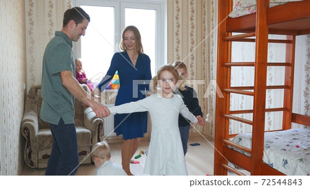 A large and friendly family plays at home and leads a round dance. 72544843