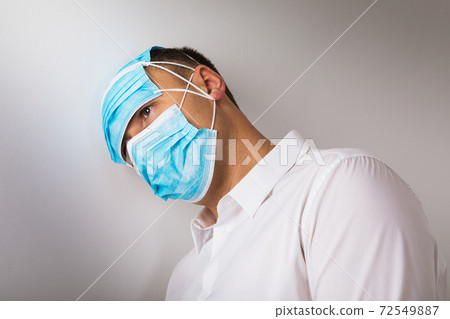 The man in medical masks leaned his head against the wall. Concept on the topic of depression due to the quarantine caused by the coronavirus 72549887