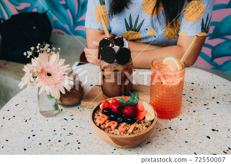 Healthy breakfast bowl with fresh berries, nuts, bananas and chocolate smoothie drink. Vegan food. 72550007