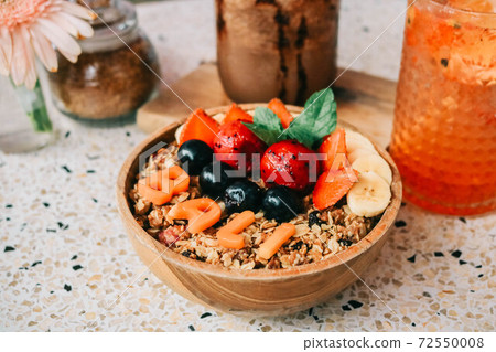 Healthy breakfast bowl with fresh berries, nuts, bananas and chocolate smoothie drink. Vegan food. 72550008