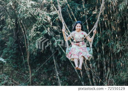 Young pretty Asian woman is swinging on the cliff of the jungle in Ubud, Bali. Young pretty Asian woman is swinging on the cliff of the jungle in Ubud, Bali. 72550129