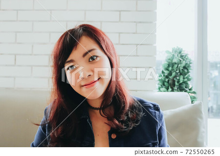 Young pretty Asian woman sitting in the cafe with nature light. Young pretty Asian woman sitting in the cafe with nature light. 72550265